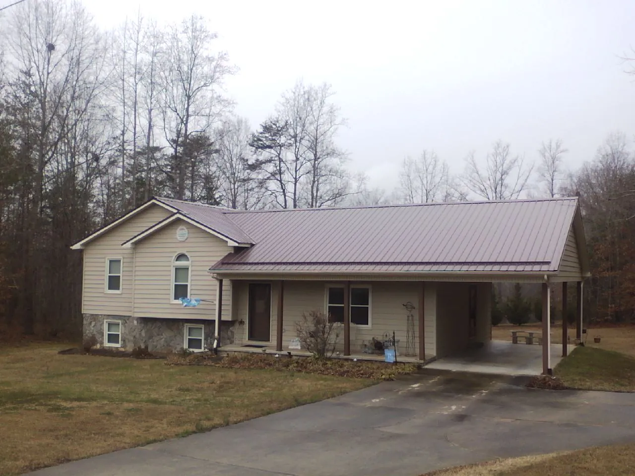 Burgundy metal roof on a tan split level home with an attached carport in Carson City