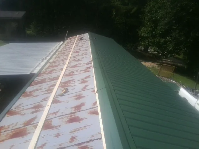 Old rusted panels beside newly installed green metal roofing — Wind Damage Roof Repair by Roofing Brothers in Carson City