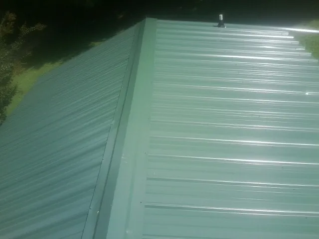 New green metal panels meeting at the ridge of a roof — Flat Roof Repair work by our crew in Carson City