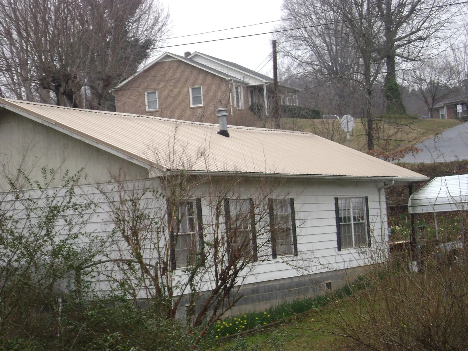 Tan metal roof on a white sided house set into a hillside — Commercial Roofing by Roofing Brothers in Carson City