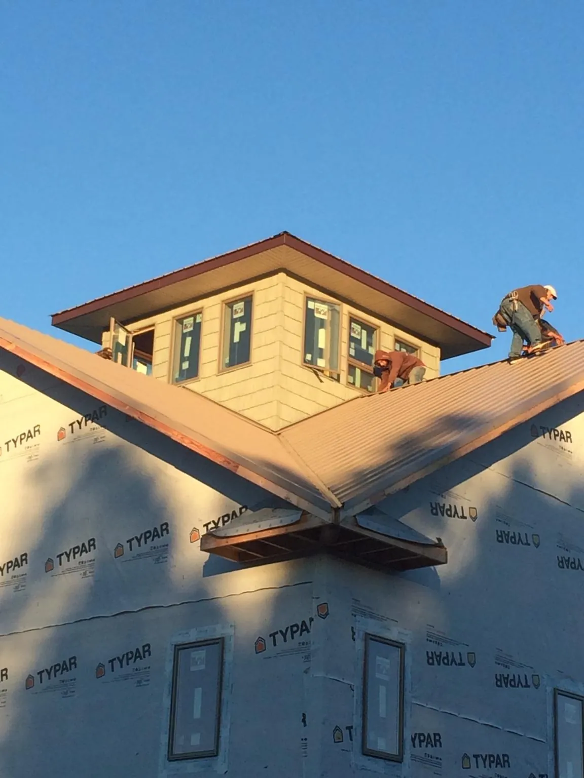 Roofers working around a rooftop cupola on a new metal roof at sunset — Roof Waterproofing in Carson City by Roofing Brothers